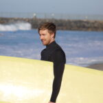 Jack Gibson, the owner of GibsonVS, holding a surf board while taking a break from virtual services.